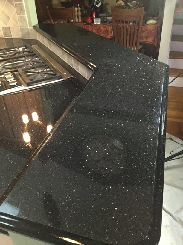 Black countertop with sparkling flecks, part of a kitchen with a stovetop visible.