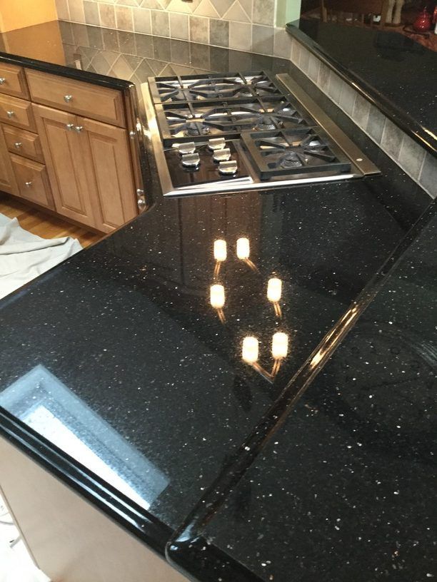Black granite countertop with built-in stove. Light cabinets and a window are visible.
