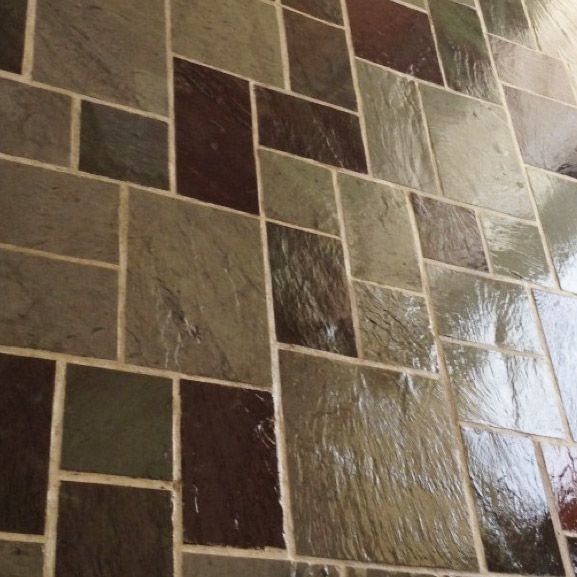 Stone tile flooring in varying shades of brown, green, and grey, arranged in a square and rectangular pattern with light grout.