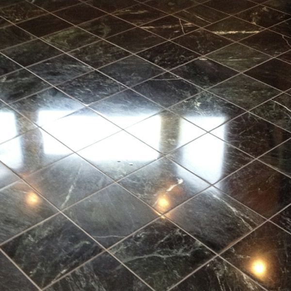 Dark green marble tile floor with a diamond pattern, reflecting sunlight.