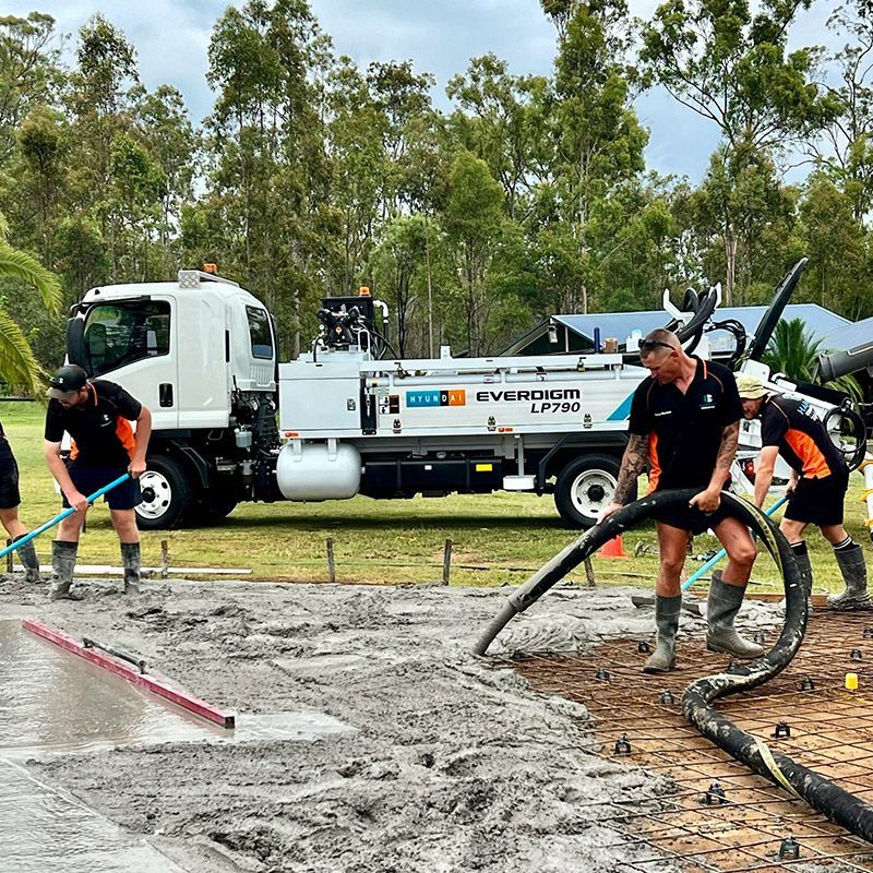 A group of men are working on a concrete floor in front of a truck.