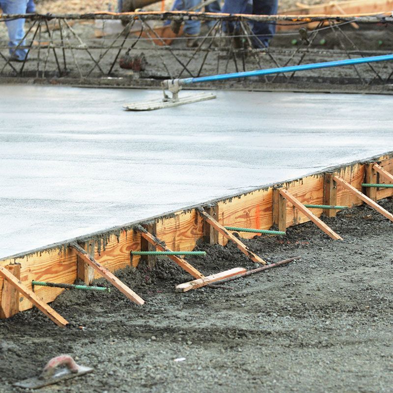 A group of construction workers are working on a concrete floor.