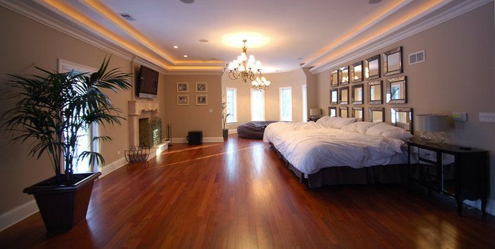 A large bedroom with hardwood floors and three beds.