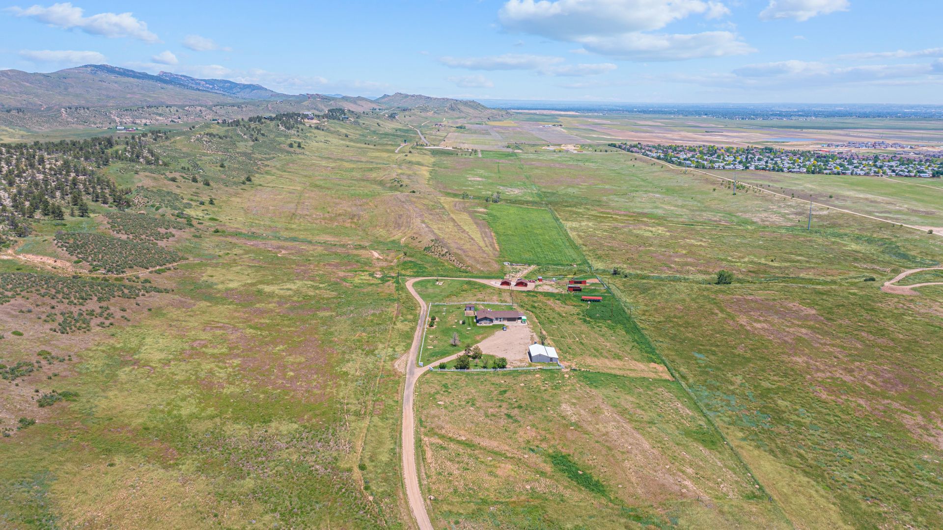 an aerial view of a farm with mountains in the background
