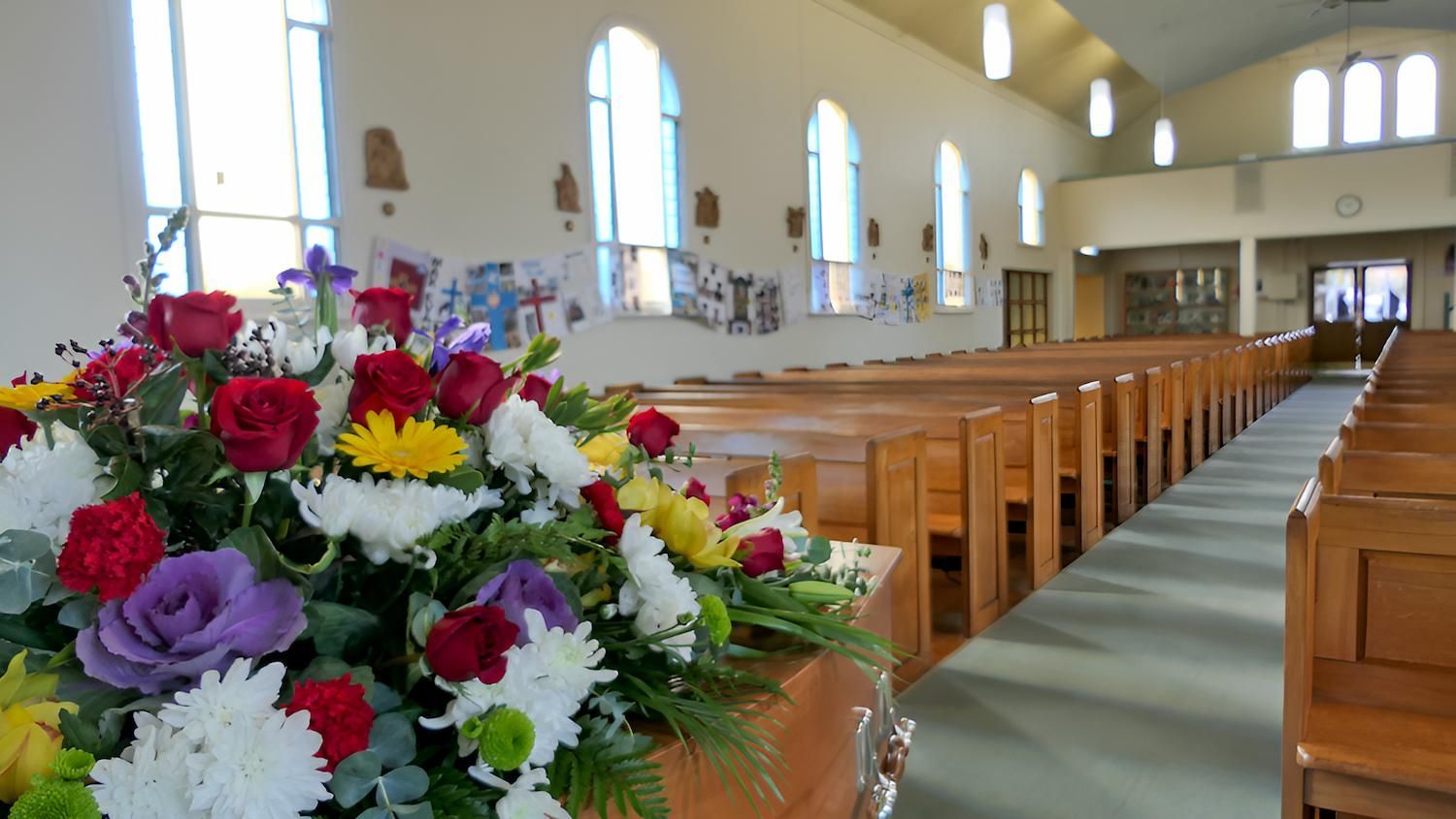 A Church With Rows of Wooden Benches and a Coffin — Mid Coast Funeral and Cremation Service In Port Macquarie, NSW