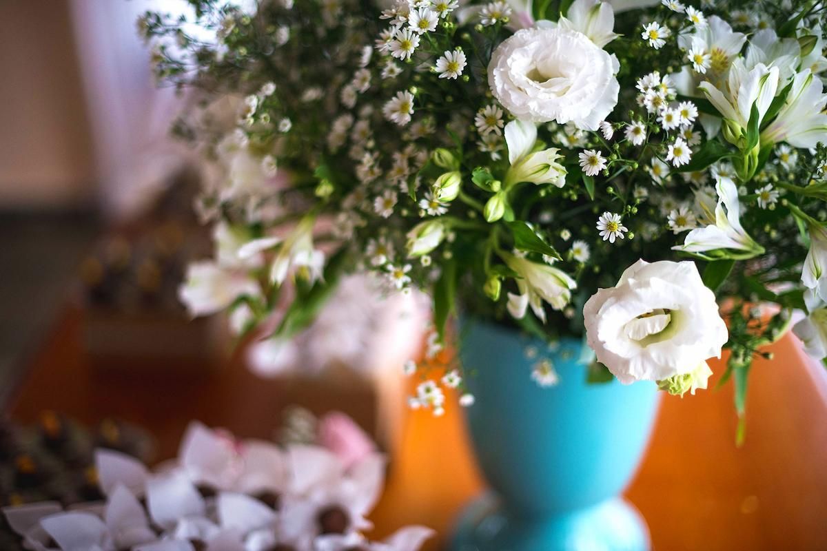A Vase Filled With White Flowers is Sitting on a Table — Mid Coast Funeral and Cremation Service In Port Macquarie, NSW