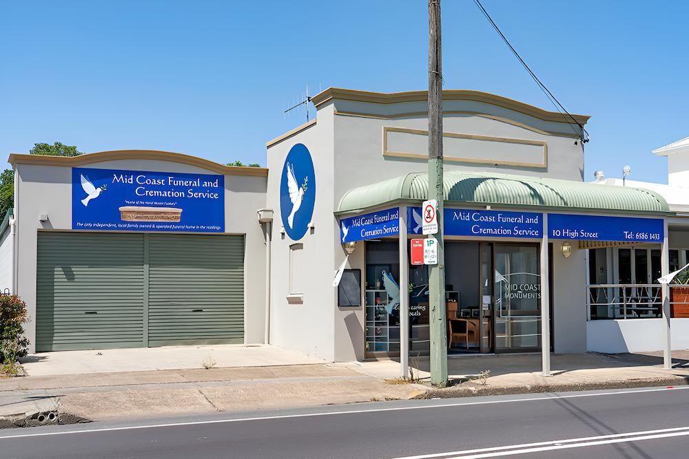 A White Building With a Blue Sign — Mid Coast Funeral and Cremation Service In Port Macquarie, NSW