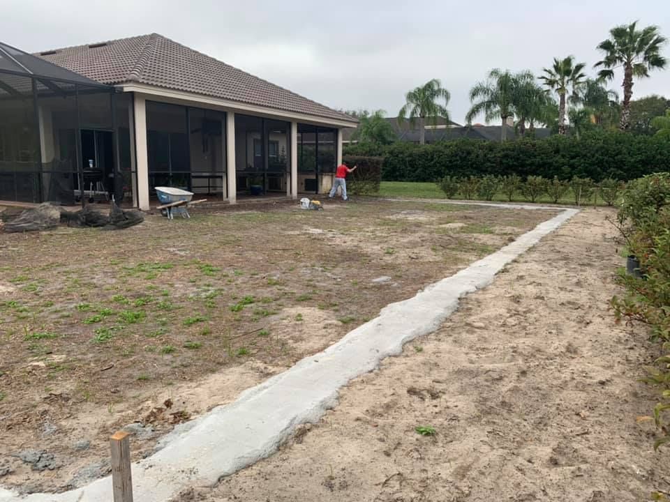 A concrete walkway is being built in the backyard of a house.