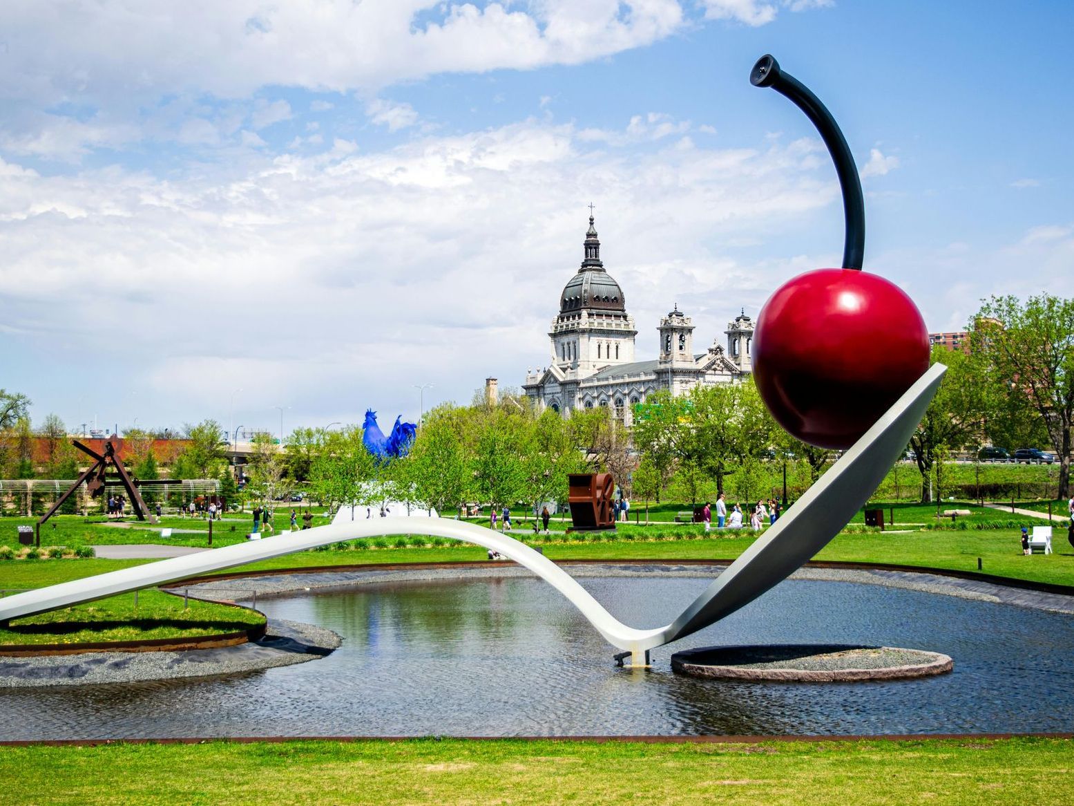 Cherry and Spoon sculpture in Minneapolis, MN, red cherry in spoon in water, park setting.