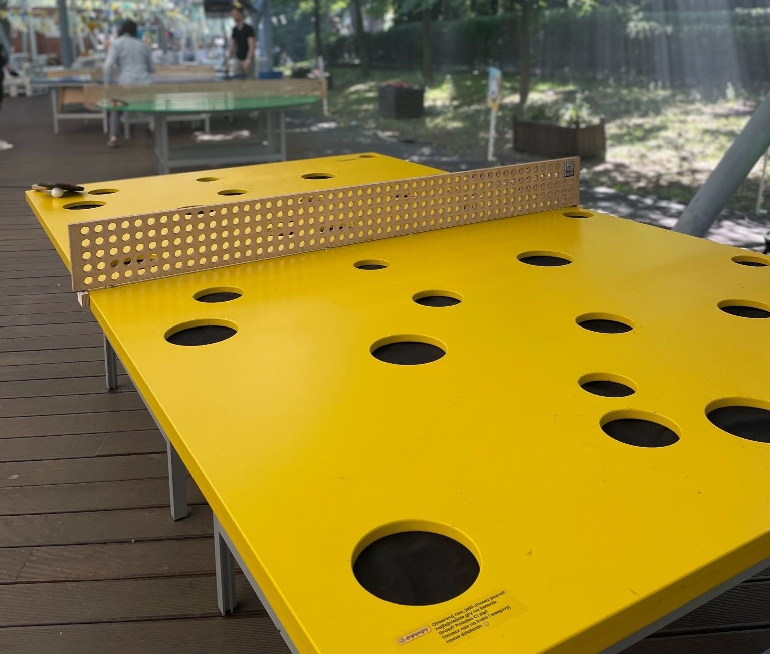 żółty stół do ping-ponga z dziurami stoi pod namiotem.