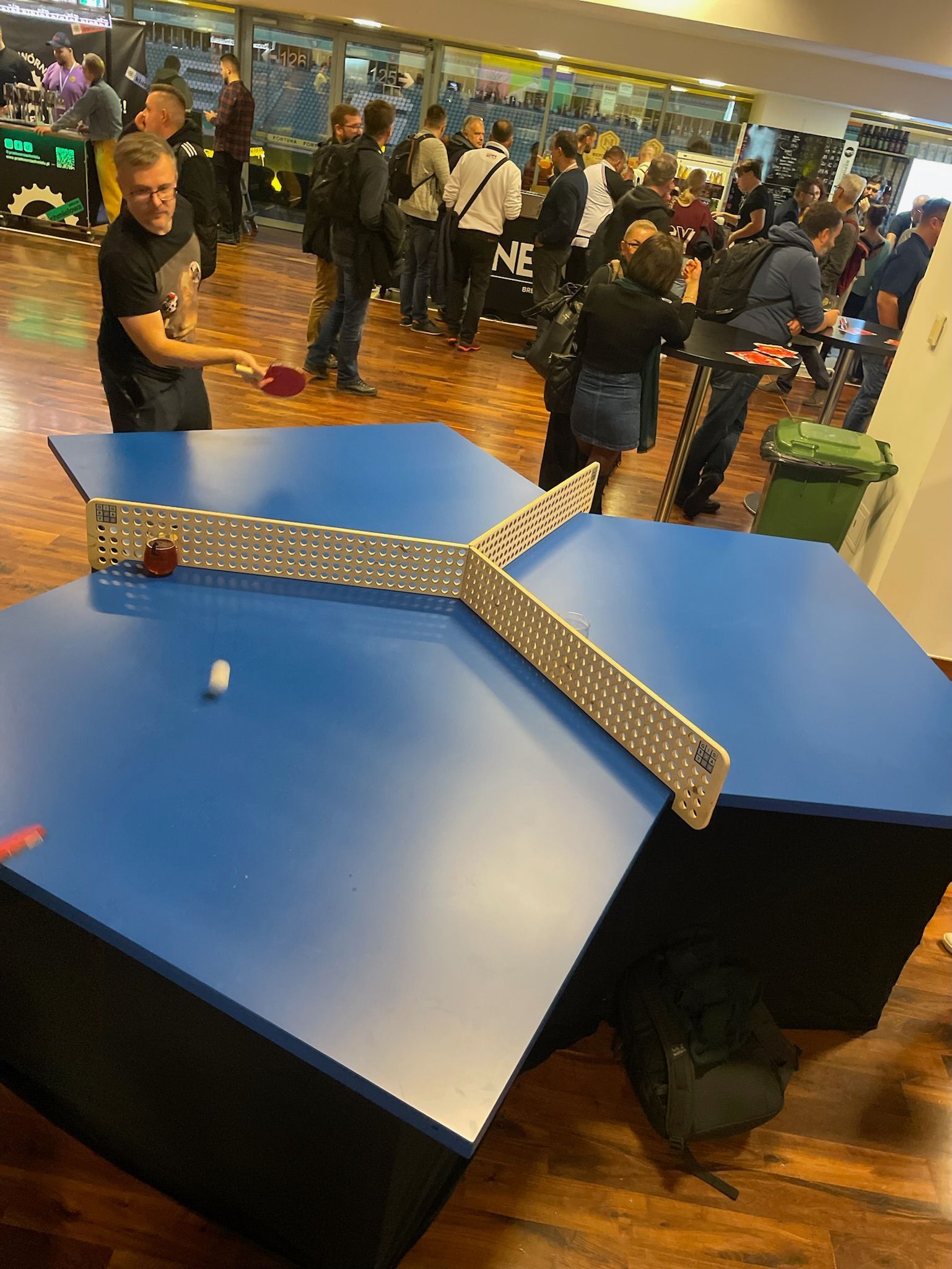 grupa ludzi gra w ping-ponga na niebieskim stole.