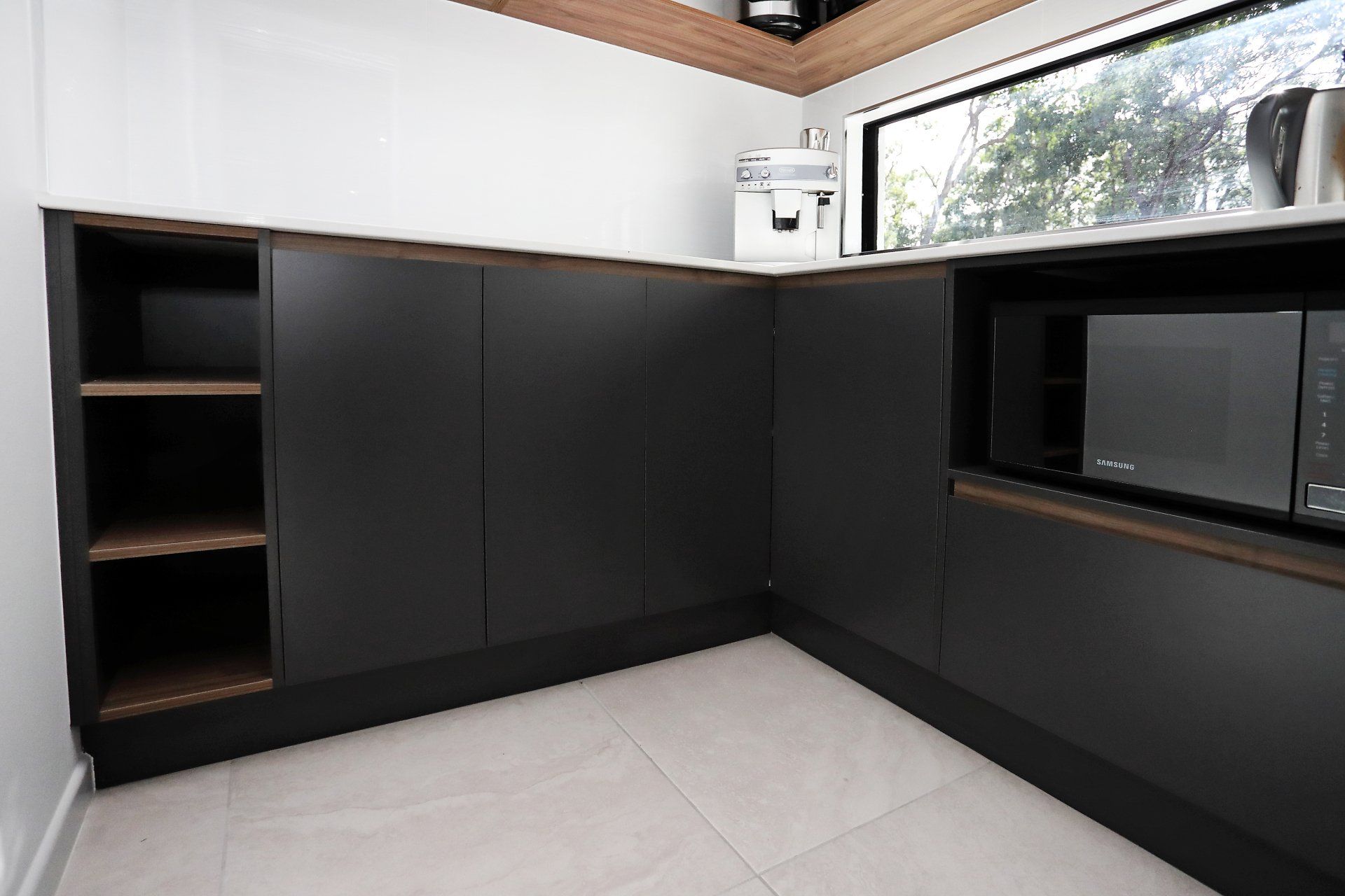 A kitchen with black cabinets and a microwave