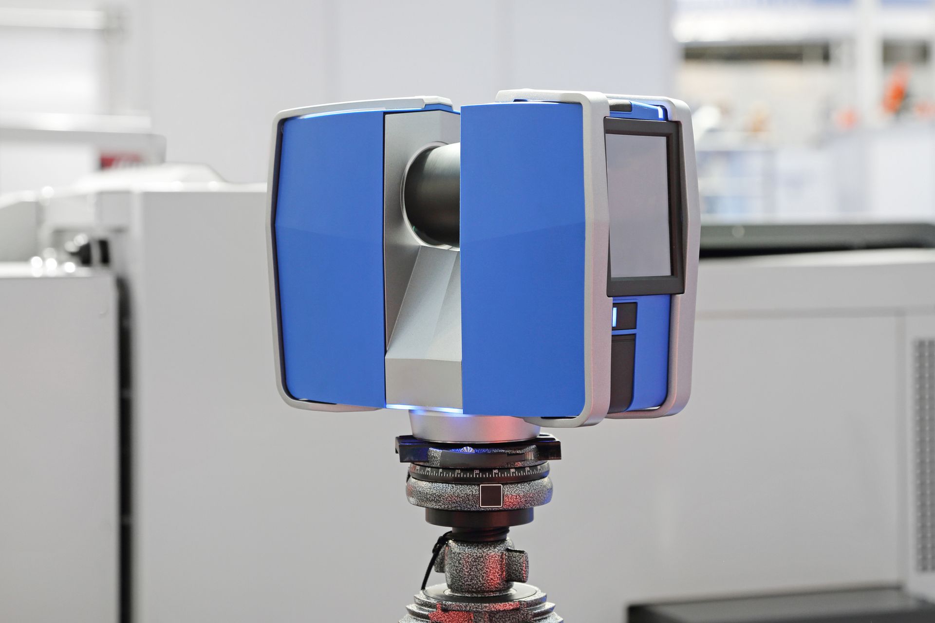 A 3D laser scanner on a tripod in an industrial setting.