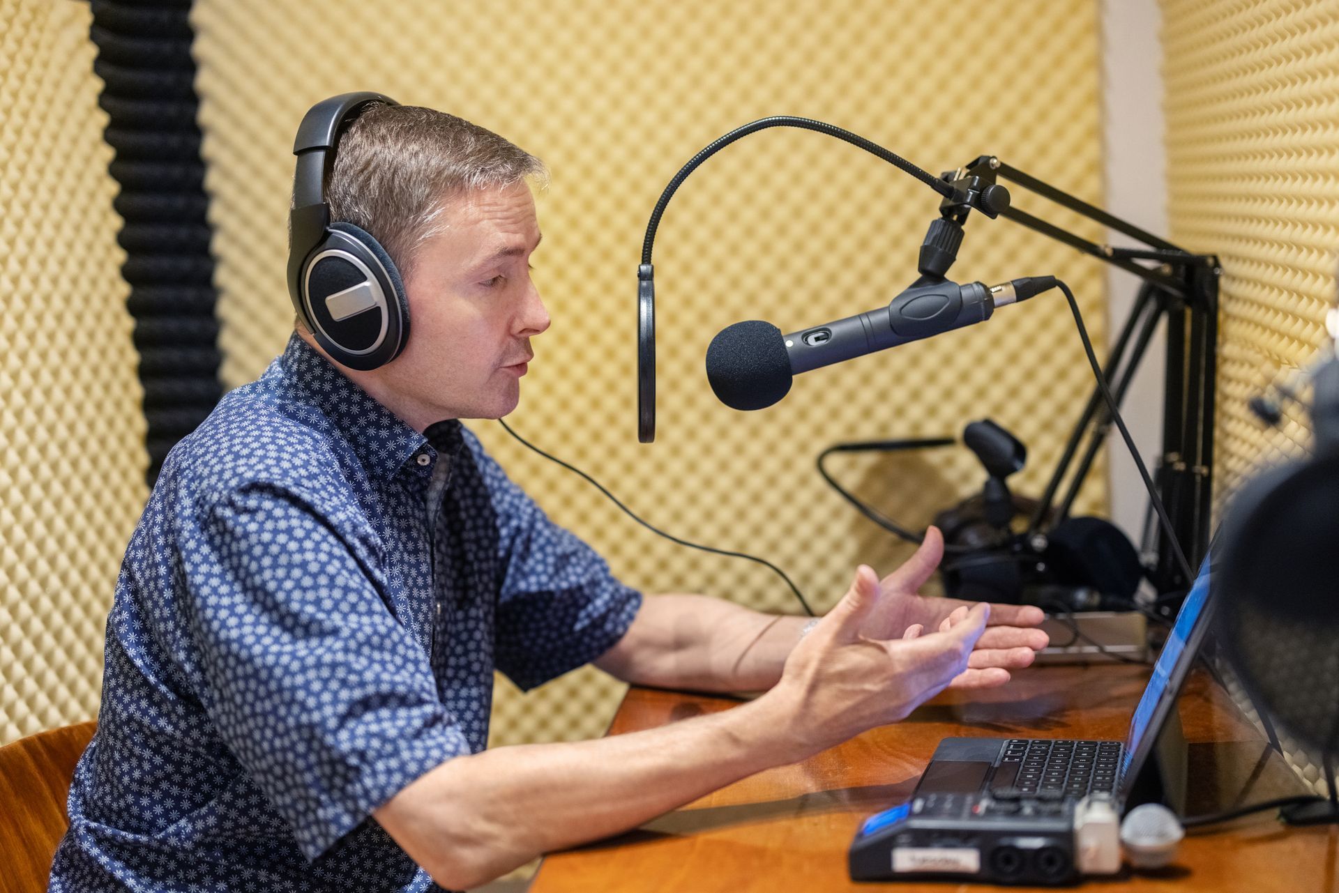 A man with headphones is recording a podcast in a soundproof studio.