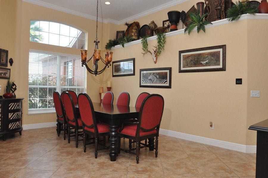 A dining room with a long table and red chairs