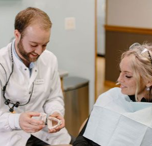 Dentist showing teeth mold to a patient in a dental office. Both are smiling.