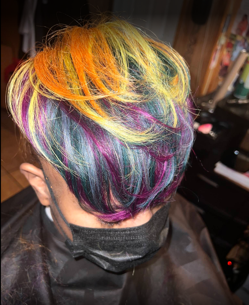 A woman with colorful hair is sitting in a chair in a salon.