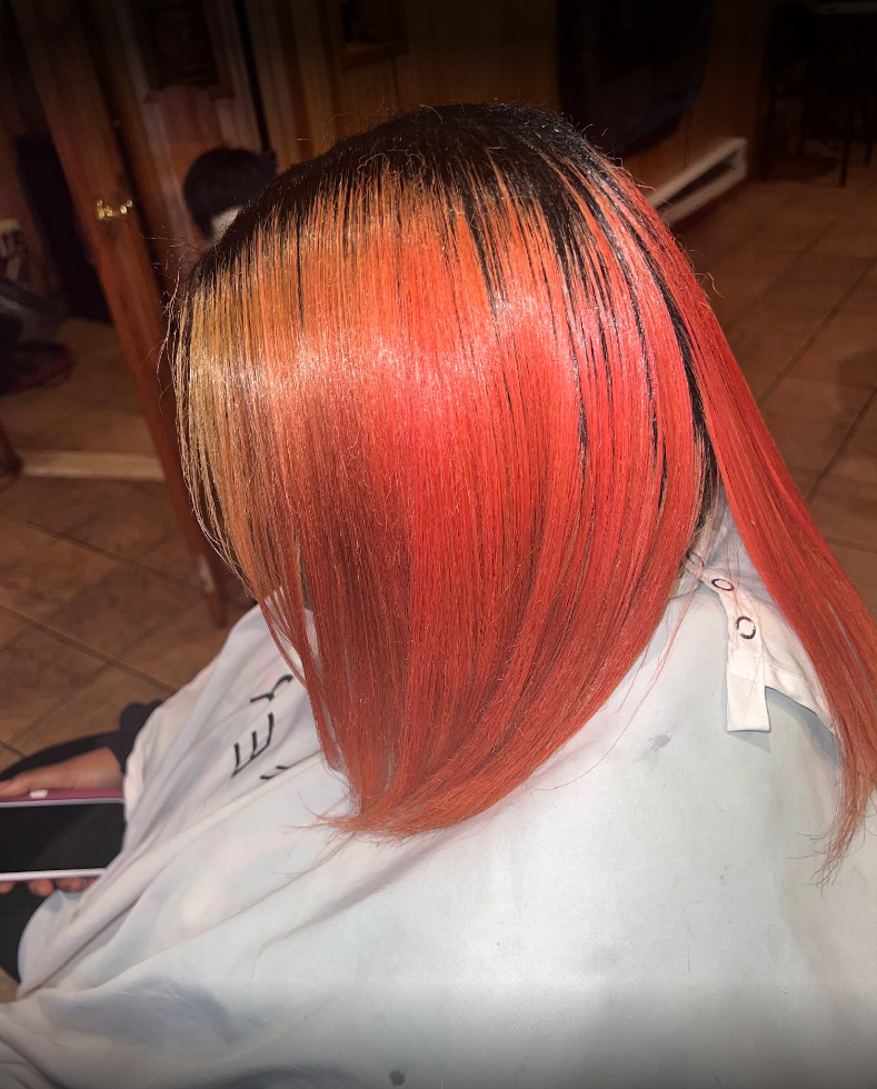 A woman with red hair is getting her hair cut in a salon.