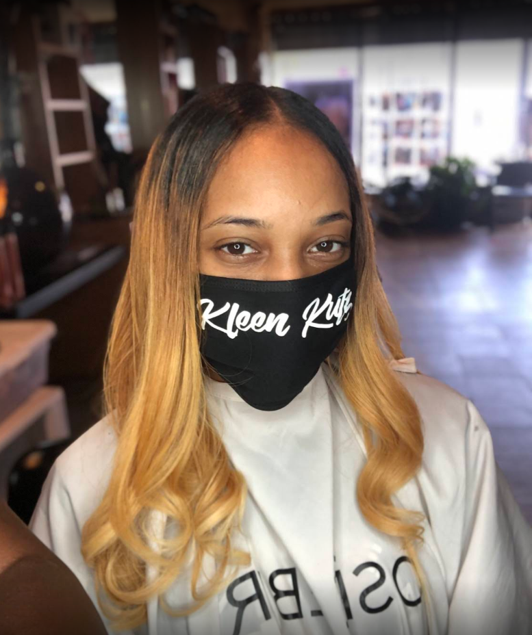 A woman wearing a black mask with the word kleen written on it.