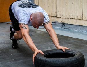 A man is doing push ups on a tire.