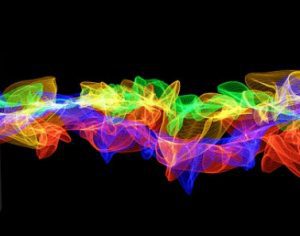 A long exposure photo of a rainbow of lights on a black background.