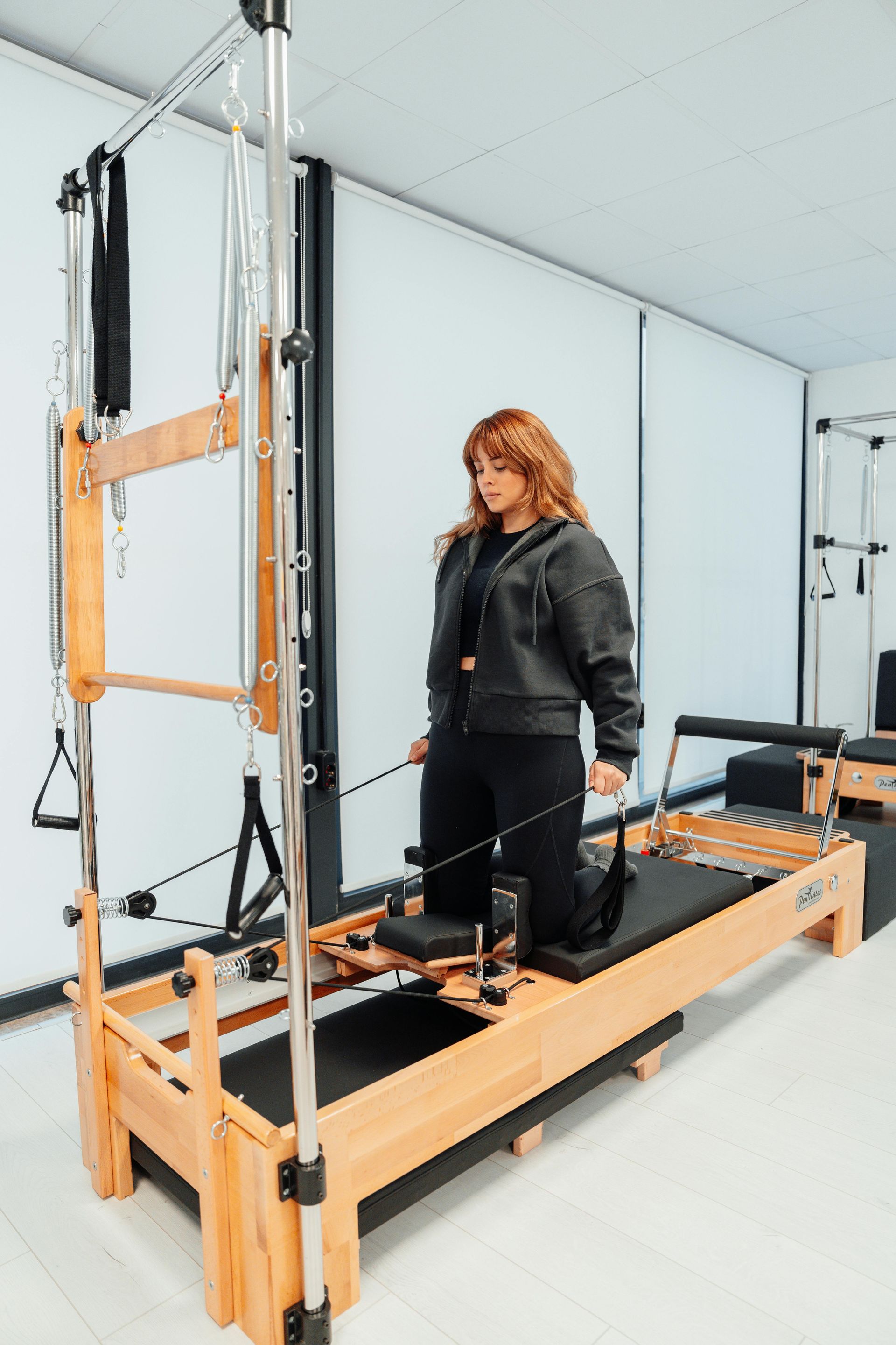 A woman is standing on a pilates machine in a gym.