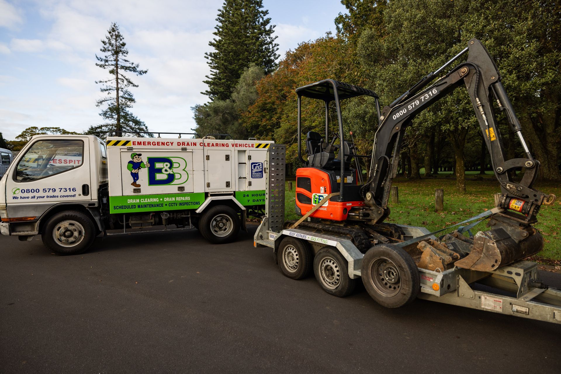 Man installing a metal pipe into an open sewer drain. Grate and ladder visible.