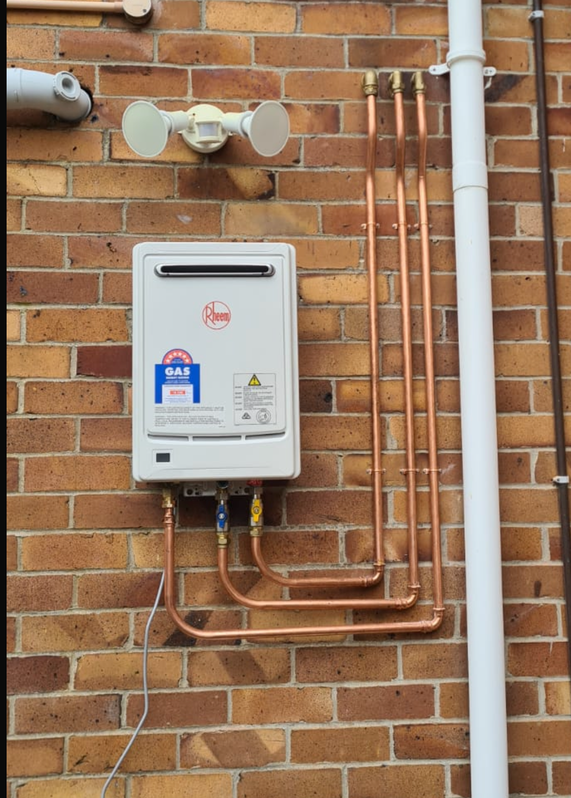 Person in red gloves adjusting valves on a water heater.