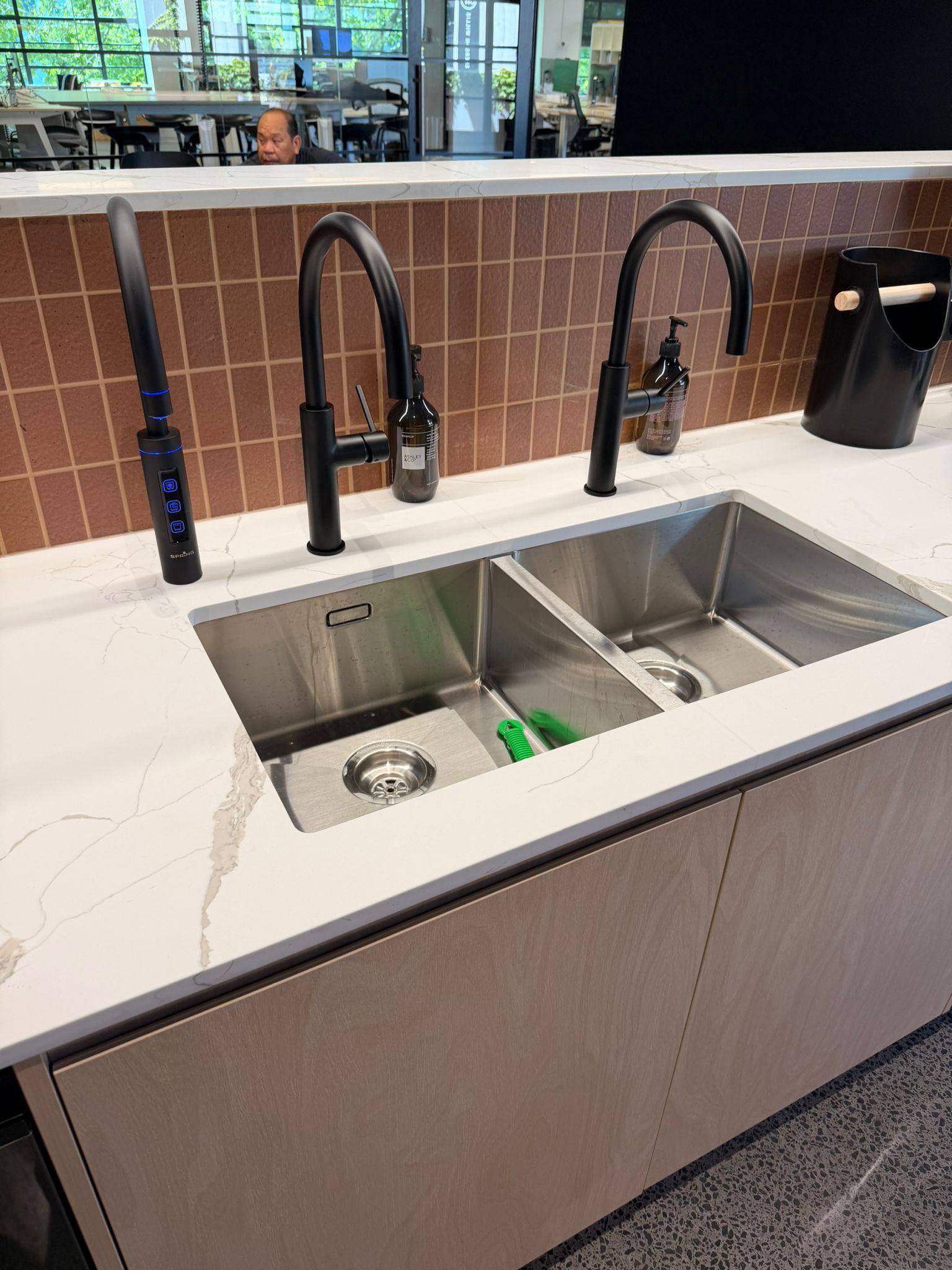 Double sink with black faucets in a kitchen setting.
