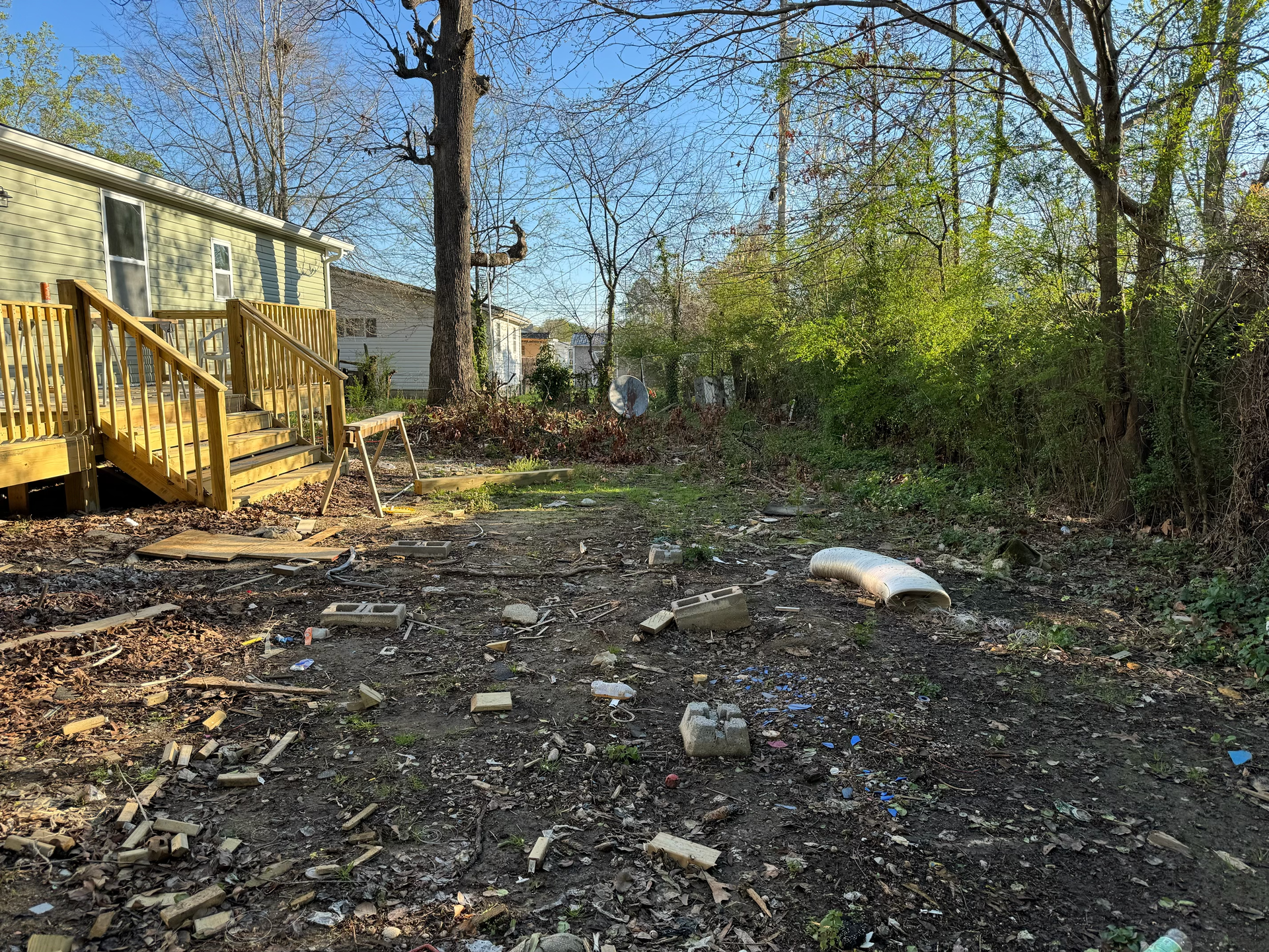 There is a lot of trash in the backyard of a mobile home.