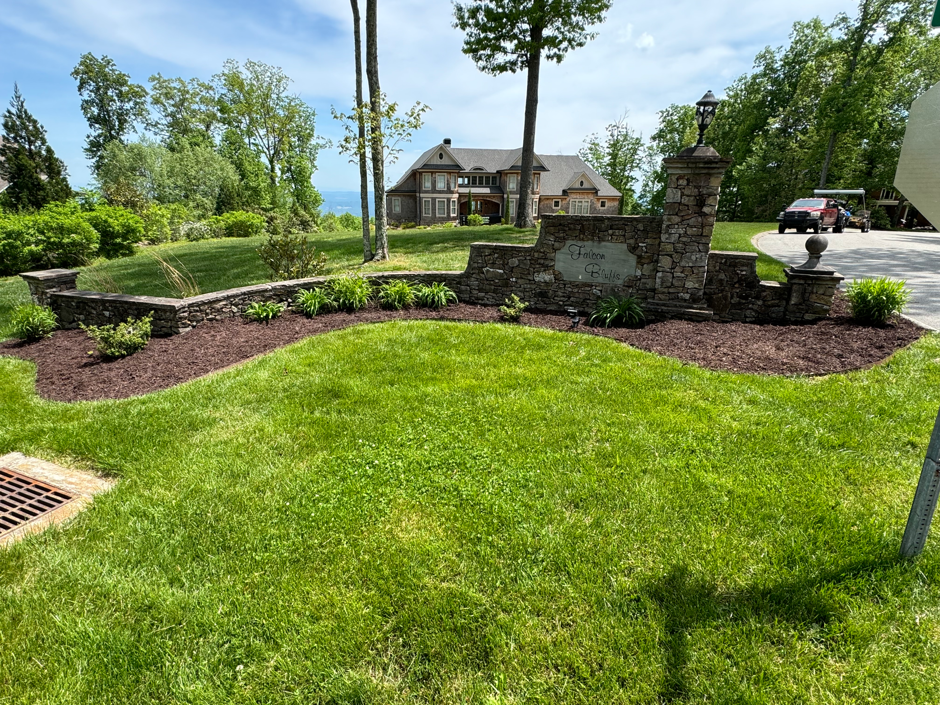 A lush green lawn with a large house in the background.