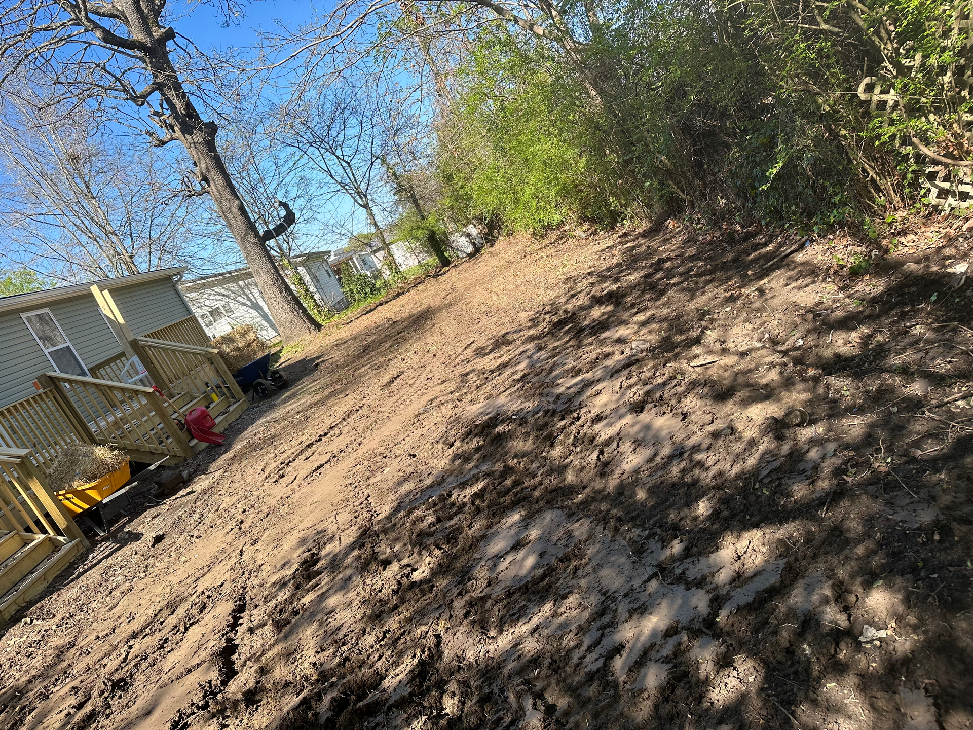 A dirt road going up a hill next to a house.