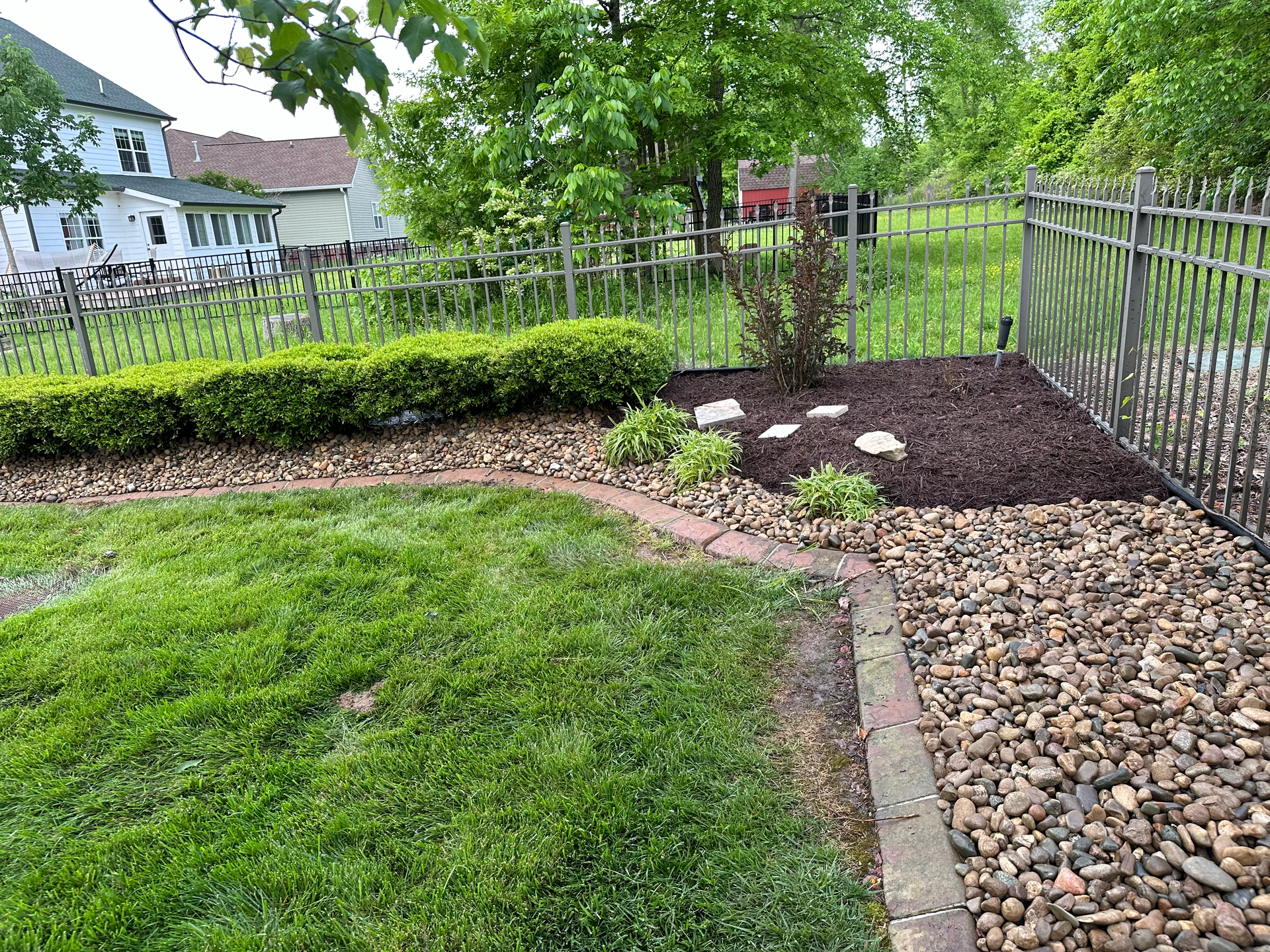 A backyard with a fence and a lush green lawn.