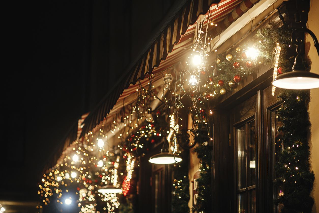 Storefront decorated with Christmas lights and garland at night.