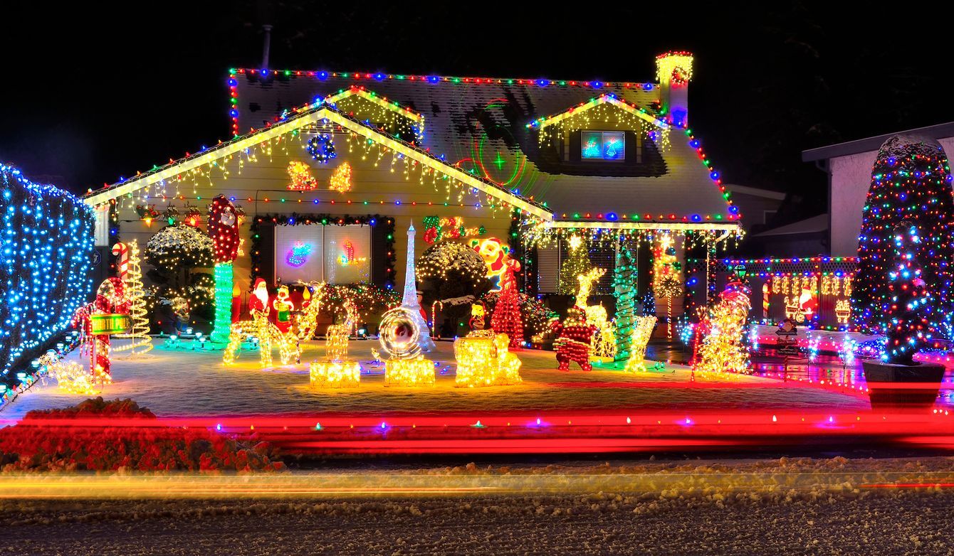 House decorated with colorful Christmas lights and holiday figures at night.