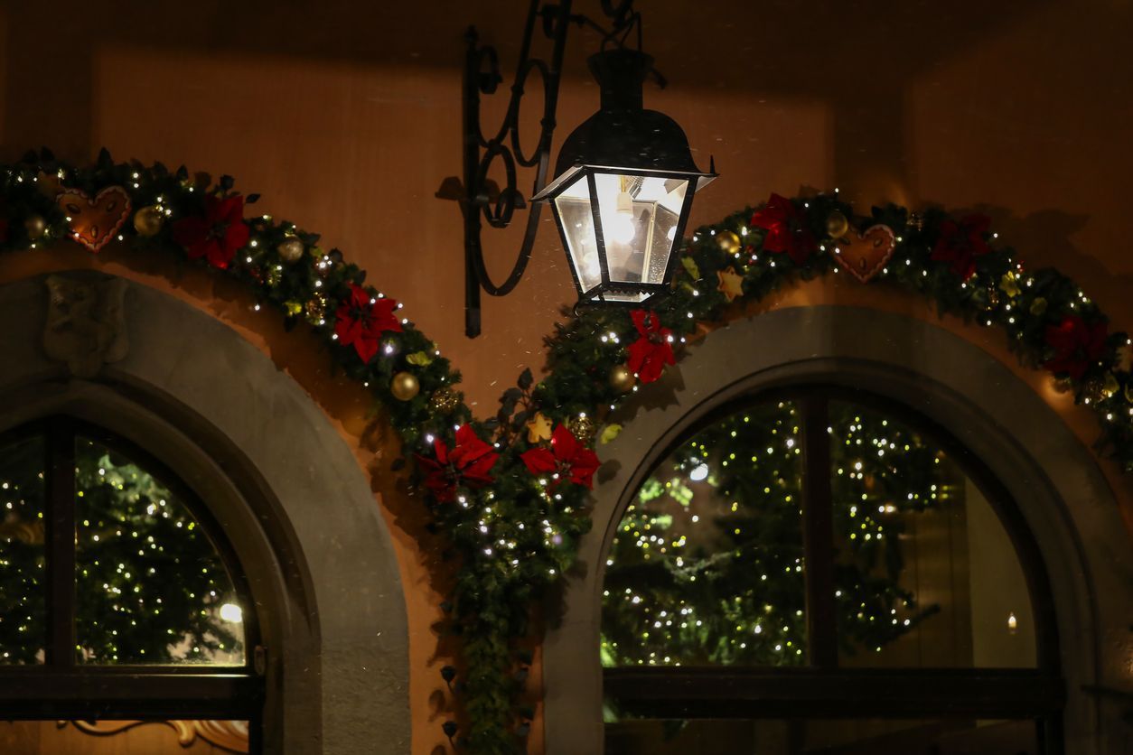 Archway decorated with Christmas garland and lights, with a lantern hanging above.