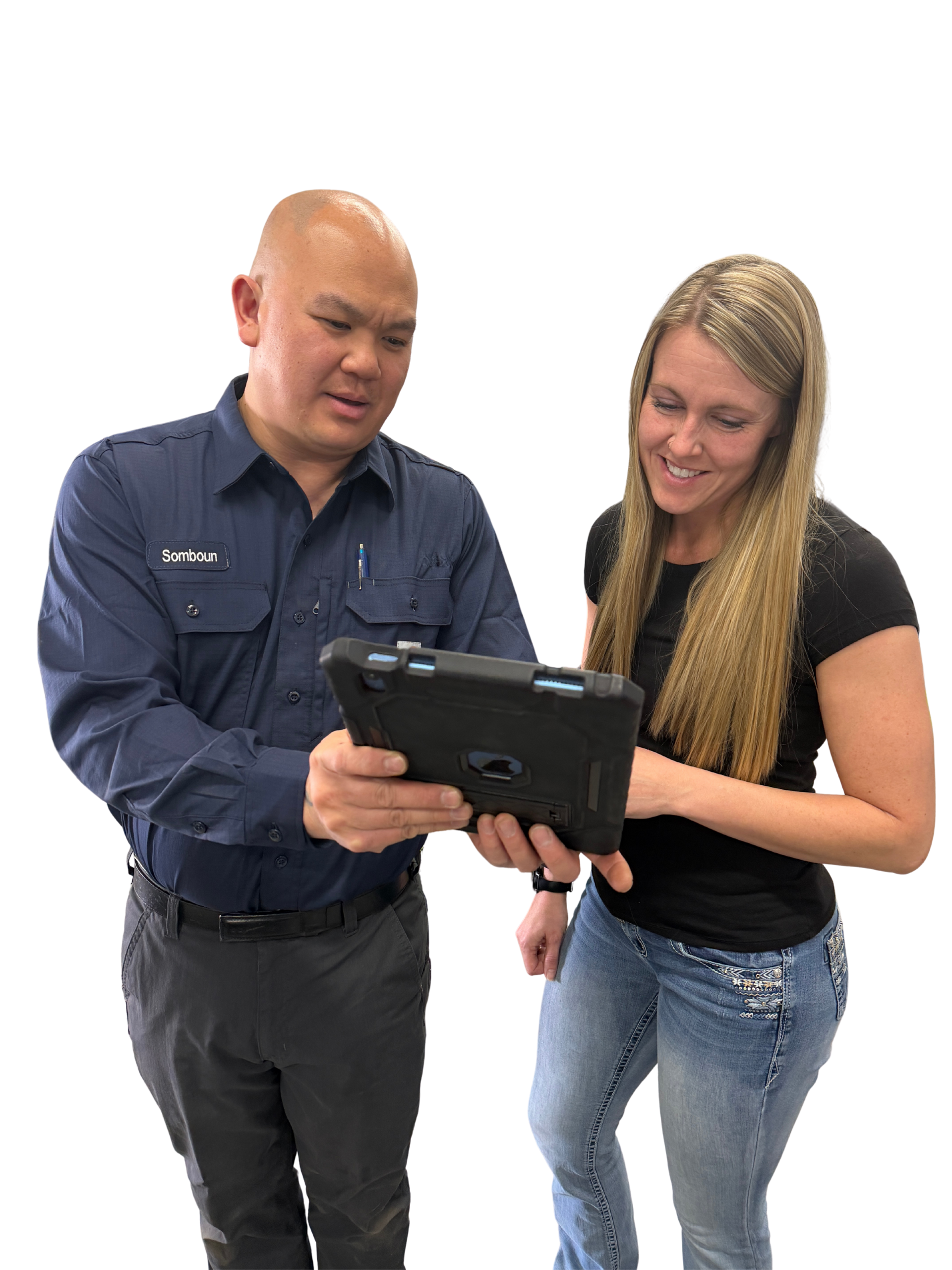 Woman and man in blue jumpsuit look at a tablet together, smiling.
