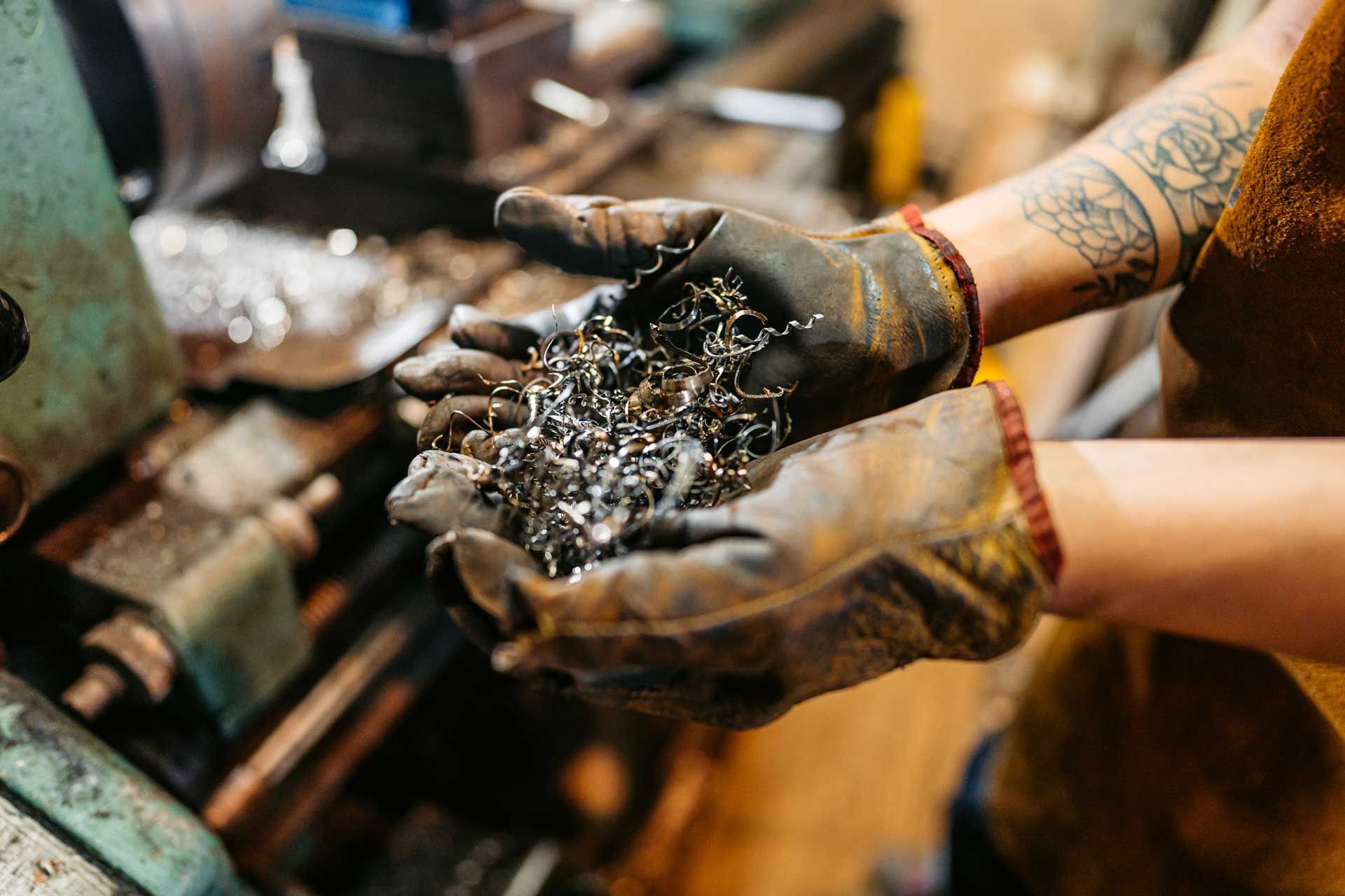 Person holding metal shavings in gloved hands in a workshop.