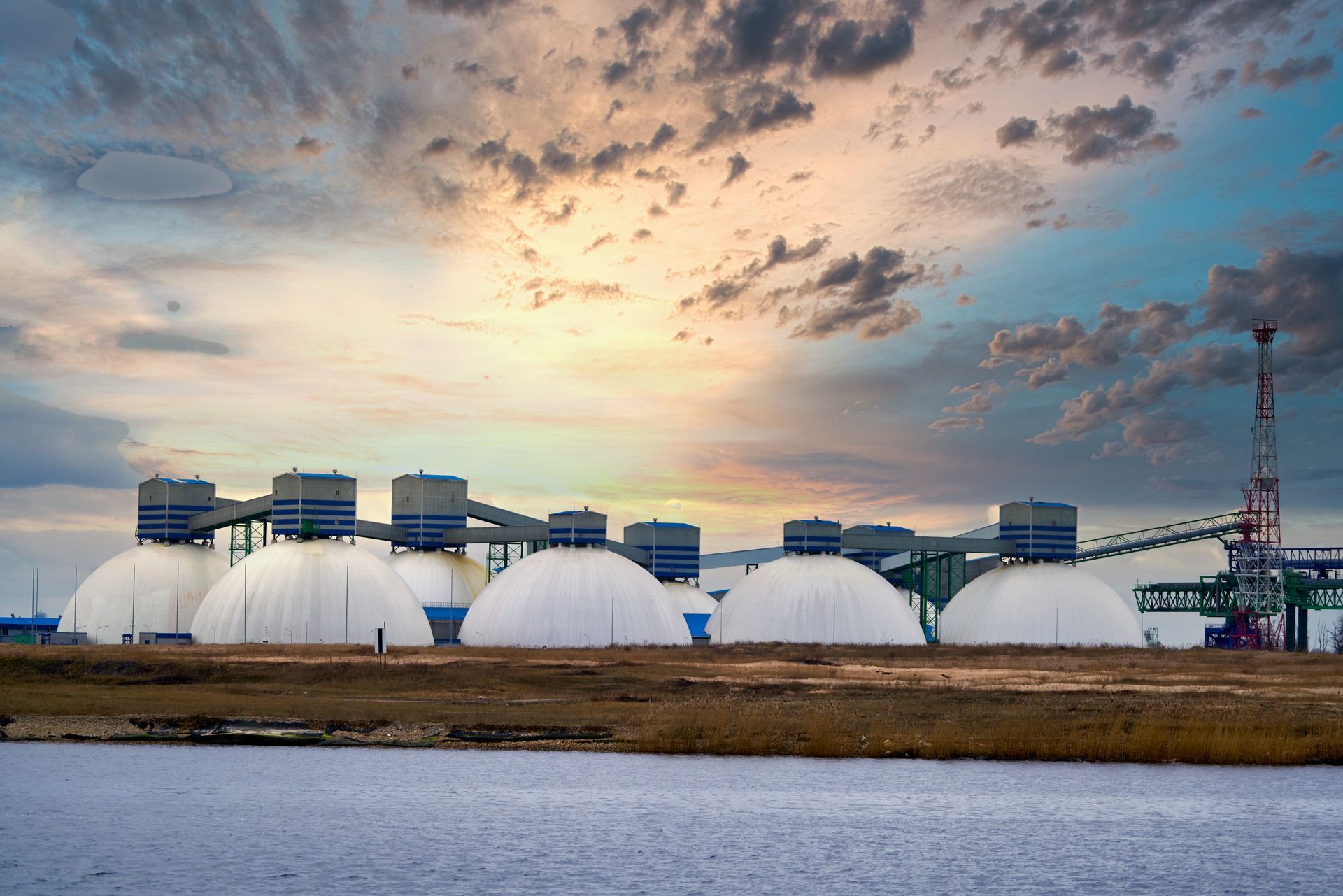 A row of large white domes sitting next to a body of water.