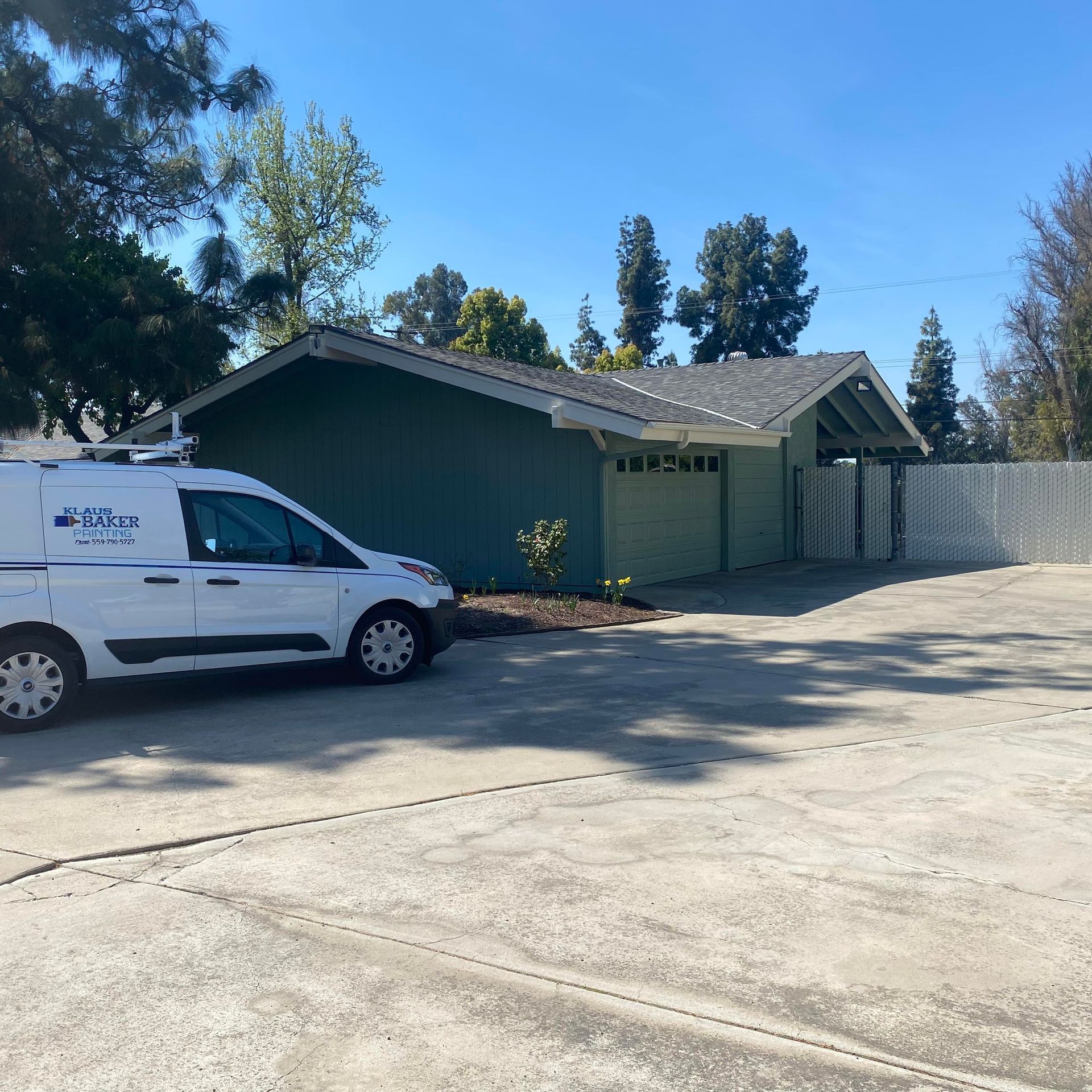 A white van is parked in front of a green house