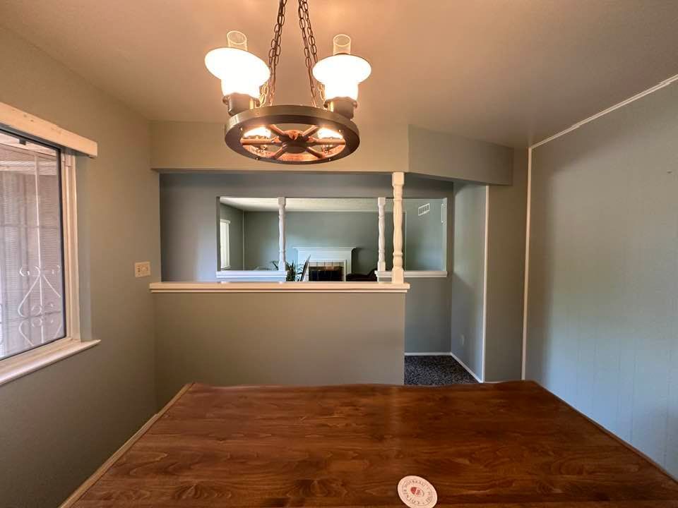 A dining room with a wooden table and a chandelier hanging from the ceiling.