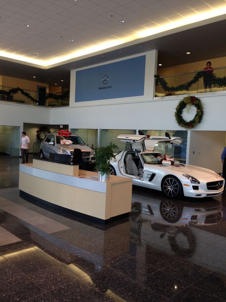 A white car is parked in the lobby of a car dealership