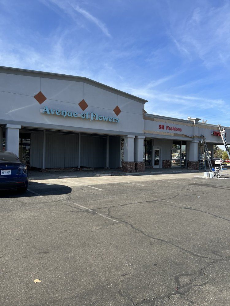 A car is parked in front of a store called five guys