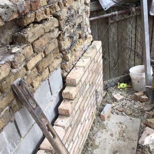 A brick wall is being built next to a wooden fence.