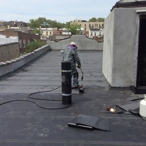 A man is working on a roof with a torch.