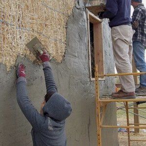 A man is standing on a scaffolding working on a wall.