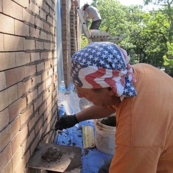 A man wearing an american flag bandana is working on a brick wall