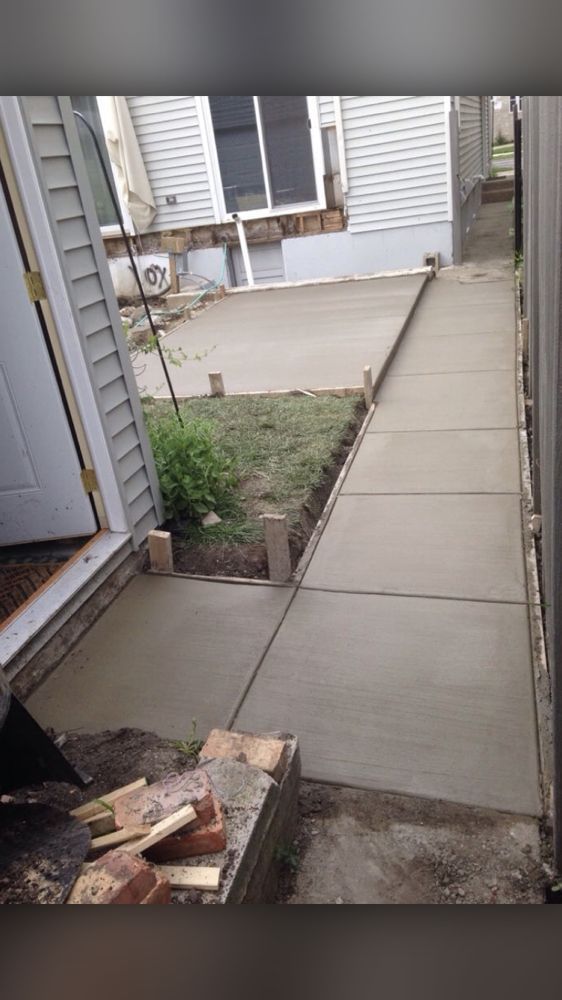 A concrete walkway is being built in front of a house.