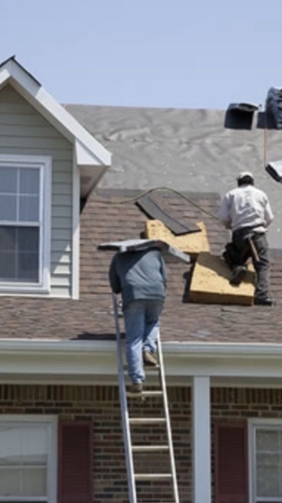 Two men are working on the roof of a house