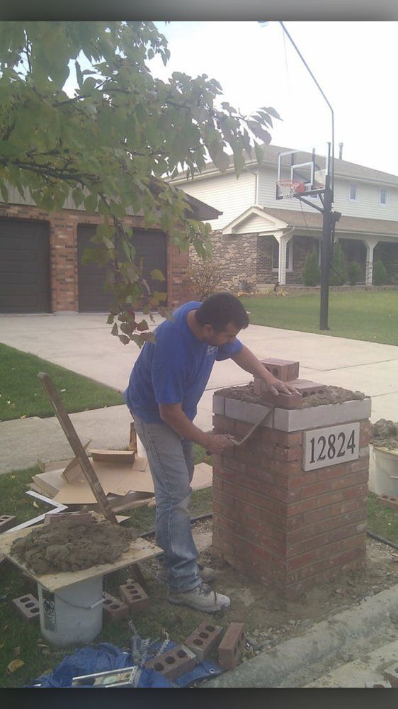 A man is working on a brick mailbox with the address 12824